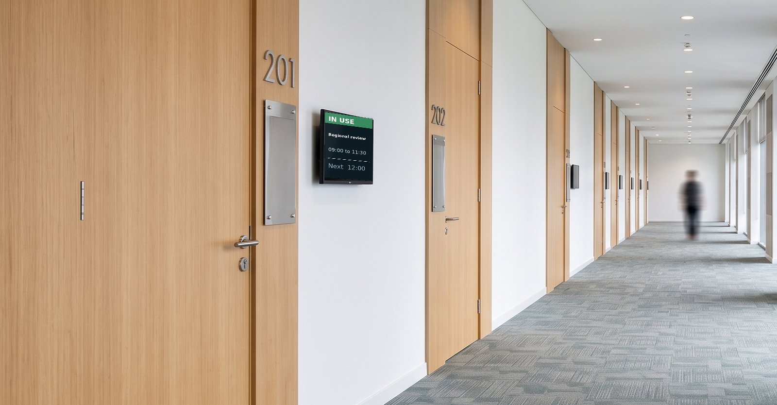 A small screen beside a meeting room door showing the meeting in progress
