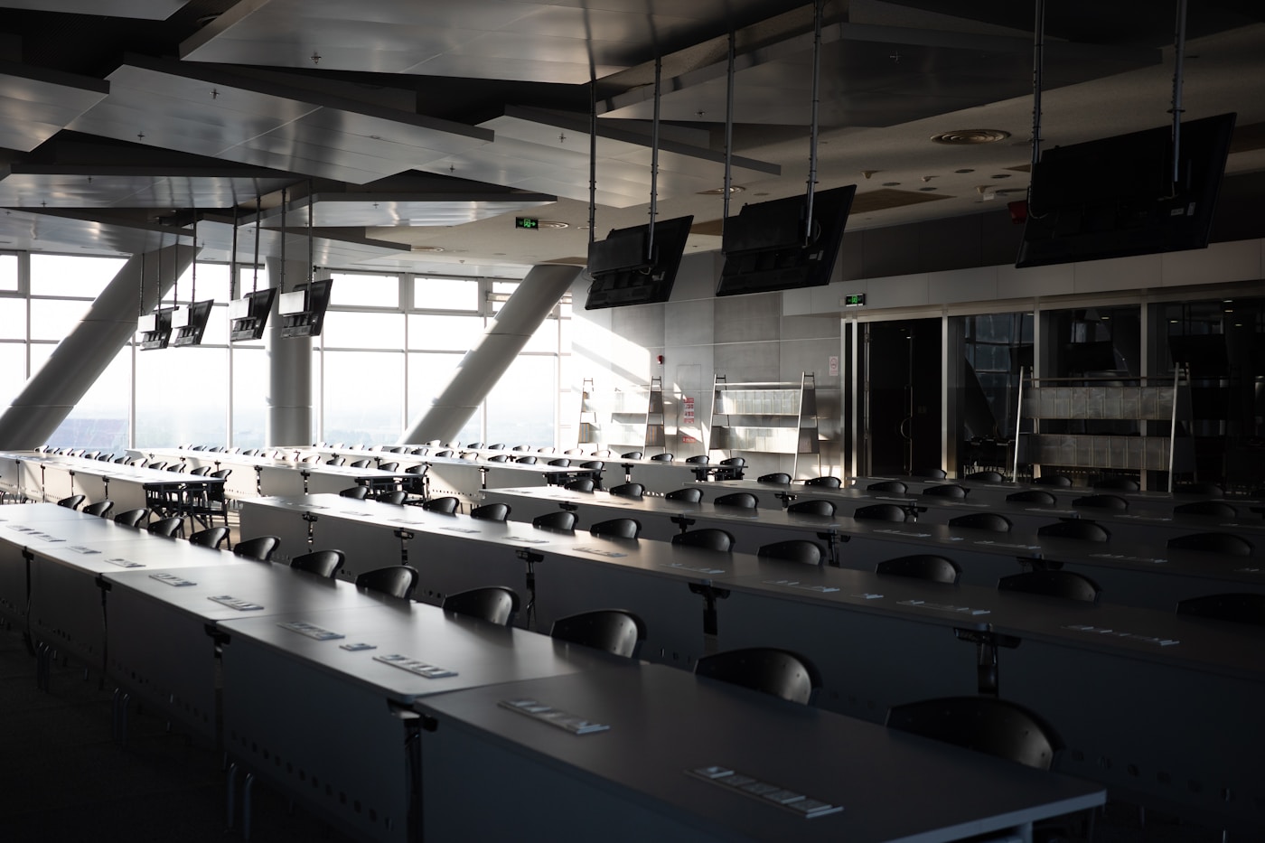 A large meeting room with several ceiling-mounted screens